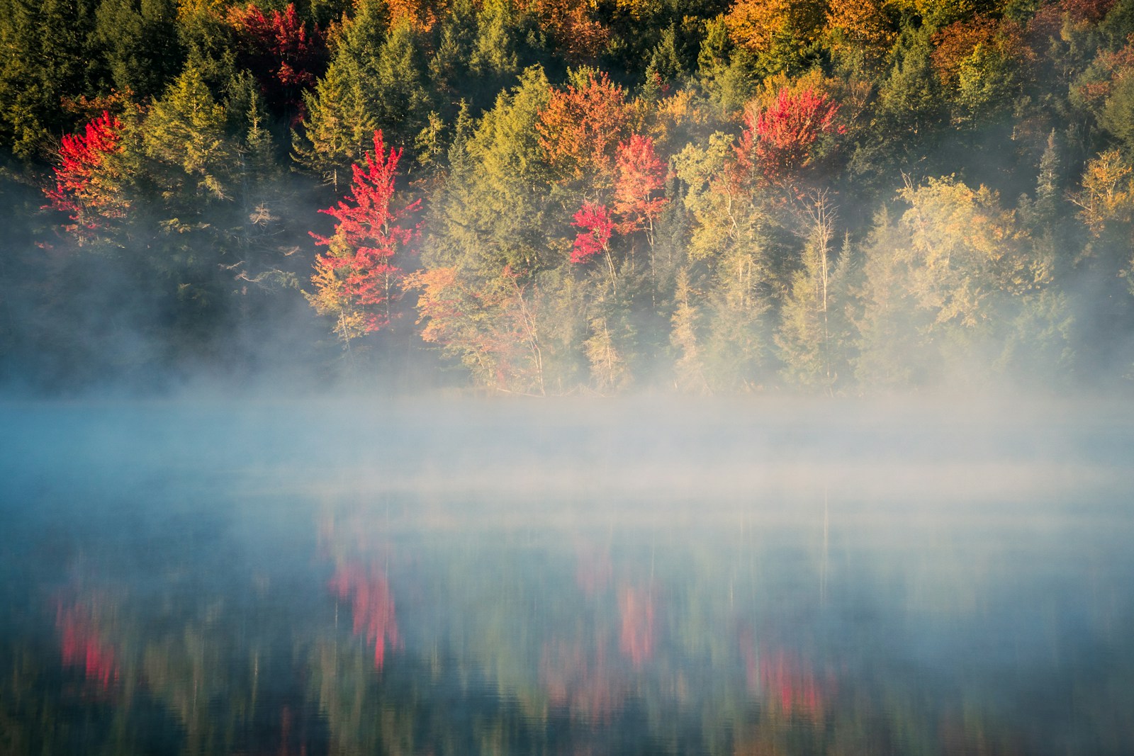 Mist rising over still water and autumn trees in Killington, Vermont